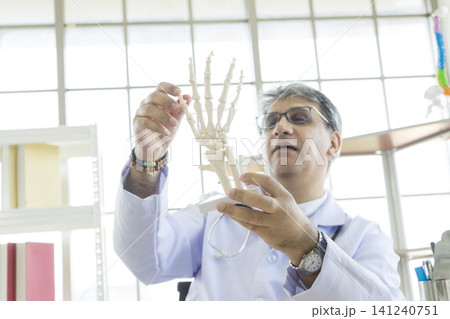 Orthopedic doctor in his office. Orthopedic doctor explain the ankle bone structure to the patient. Orthopedic doctor in his office. Orthopedic doctor explain the ankle bone structure to the patient. 141240751