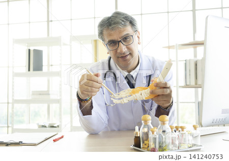 Orthopedic doctor in his office. Orthopedic doctor explain the ankle bone structure  to the patient. 141240753