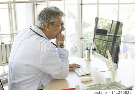 Orthopedic doctor working on his computer in his office. Orthopedic doctor with ankle bone structure model on table. 141240826