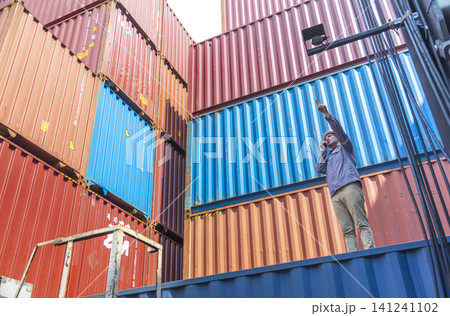 Happy Winner manager, Foreman shipping staff working at Container cargo rising hand and pointing finger for Win in Logistic Business. Leader stand on above container. Happy Winner manager, Foreman shipping staff working at Container cargo rising hand and pointing finger for Win in Logistic Business. Leader stand on above container. 141241102