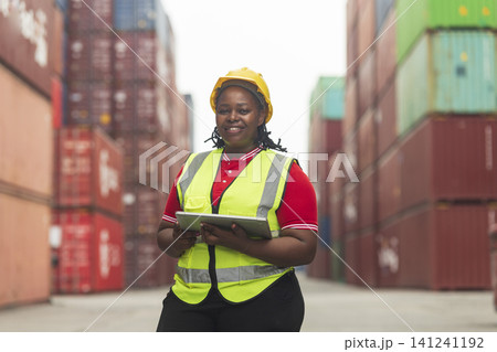 Black African woman staff worker check inventory in port cargo shipping yard warehouse. Black African woman staff worker check inventory in port cargo shipping yard warehouse. 141241192