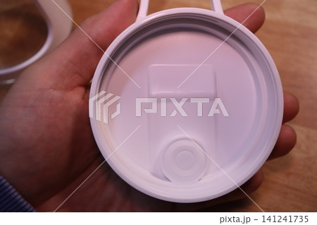 Close-up of White Cup Lid Held in Hand Close-up of White Cup Lid Held in Hand 141241735
