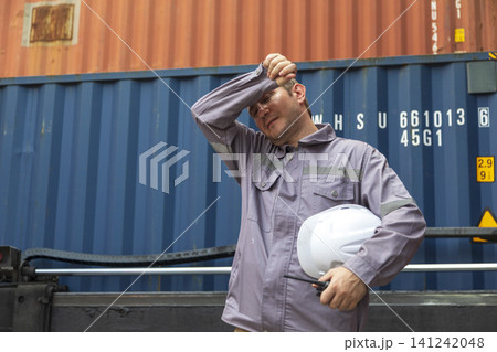 American engineer in uniform holding hard hat standing in containers yard, worker tired of frustration.  141242048