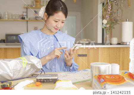 スマホを使って防災用品を確認する女性 141242135