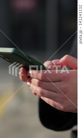 Vertical video Woman hands using smartphone outdoors on city. Searching or social networks concept. Vertical video Woman hands using smartphone outdoors on city. Searching or social networks concept. 141243132