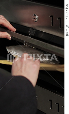 Vertical video Close-up woman is opening her mailbox and taking out of her mail in her apartment building. Mail shipping concept. Vertical video Close-up woman is opening her mailbox and taking out of her mail in her apartment building. Mail shipping concept. 141243190
