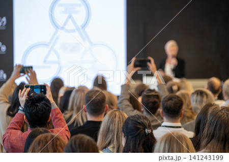 Audience recording keynote presentation at business conference, people taking photos with phones Audience recording keynote presentation at business conference, people taking photos with phones 141243199