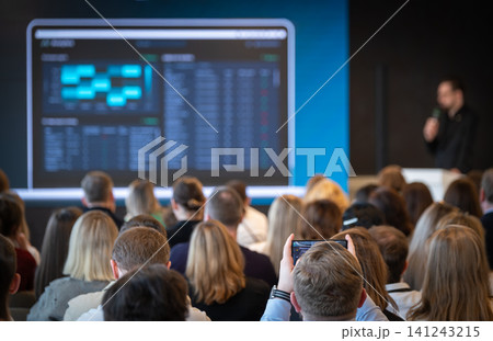 Business conference audience watching presentation with presenter and projected data screen Business conference audience watching presentation with presenter and projected data screen 141243215