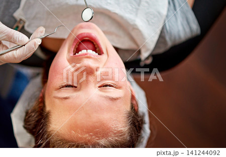 Child, dentist and open mouth with tools or doctor for checkup, consulting room or oral hygiene. Boy, dental work and above with scaler for medical in clinic, expertise or treatment with equipment 141244092