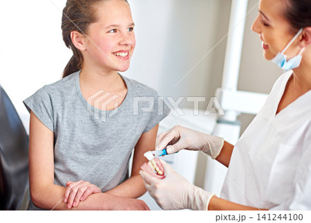 Dentures, child and orthodontics with toothbrush for teaching on oral hygiene, gum disease and dental care. Consultation, young girl and dentist holding teeth for cleaning, treatment and wellness Dentures, child and orthodontics with toothbrush for teaching on oral hygiene, gum disease and dental care. Consultation, young girl and dentist holding teeth for cleaning, treatment and wellness 141244100
