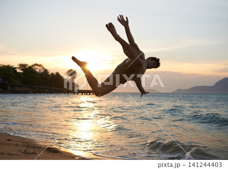 Man, dancer and breakdance with jump on beach for hip hop performance, workout training and practice. Ocean, dancing and movement with energy at sunset, stunt or flexible talent on Maldives holiday Man, dancer and breakdance with jump on beach for hip hop performance, workout training and practice. Ocean, dancing and movement with energy at sunset, stunt or flexible talent on Maldives holiday 141244403