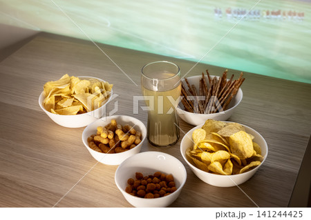 Assorted snacks and a beverage arranged on a tabletop, illustrating a game day snack table prepared for football fans. Assorted snacks and a beverage arranged on a tabletop, illustrating a game day snack table prepared for football fans. 141244425