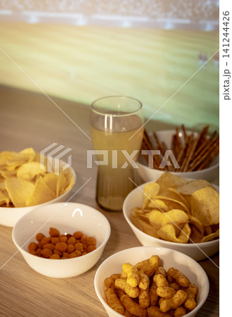 Assorted snacks and a beverage arranged on a tabletop, illustrating a game day snack table prepared for football fans. Assorted snacks and a beverage arranged on a tabletop, illustrating a game day snack table prepared for football fans. 141244426