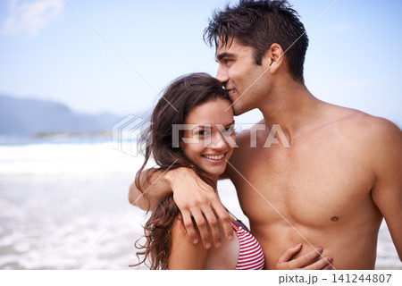 Love, embrace and portrait of happy couple at ocean for tropical holiday adventure, relax and bonding together. Nature, man and woman smile on romantic date with beach, blue sky and hug on vacation. 141244807