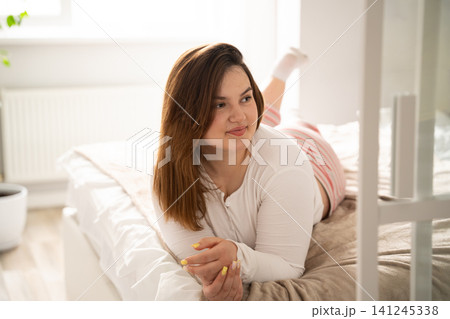 Young woman enjoying a serene morning in bed at home. Self care and mental wellness through home relaxation and morning routine 141245338