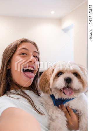 Playful teenage girl taking selfie with her small dog at home UGC 141245825