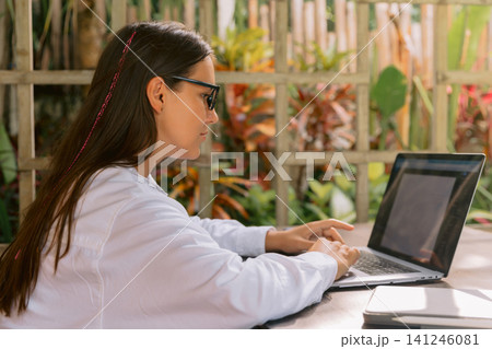 Wwoman working on laptop outdoors with natural background Wwoman working on laptop outdoors with natural background 141246081