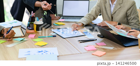 Business Team Brainstorming Meeting with Laptops, Charts, and Colorful Sticky Notes on Office Table Business Team Brainstorming Meeting with Laptops, Charts, and Colorful Sticky Notes on Office Table 141246500