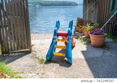 Plastic Children Slide on Lake Shore with Beautiful Nature and Water Background in Austria Plastic Children Slide on Lake Shore with Beautiful Nature and Water Background in Austria 141246587