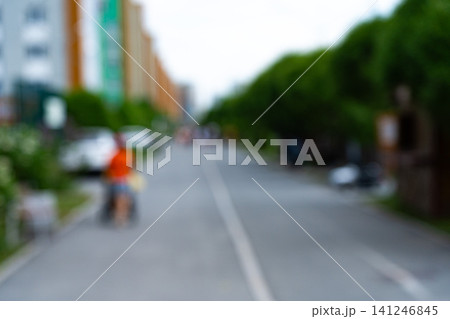 A Blurred Perspective of a Tranquil Urban Street with Lush Greenery and Mild Activity Creating an Ambiance of Relaxation and Everyday Life 141246845