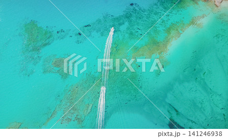 Top down drone view of two speedboats leaving white foam trails on crystal clear turquoise sea water with scenic reef sandy bottom in Balos lagoon Crete 141246938