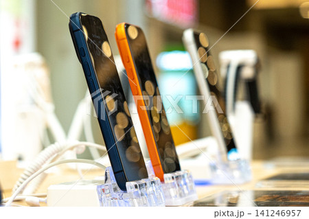 Showcasing Modern Smartphones with Unique Designs Displayed Elegantly on Stands in a Retail Setting with Soft Background Lighting Showcasing Modern Smartphones with Unique Designs Displayed Elegantly on Stands in a Retail Setting with Soft Background Lighting 141246957