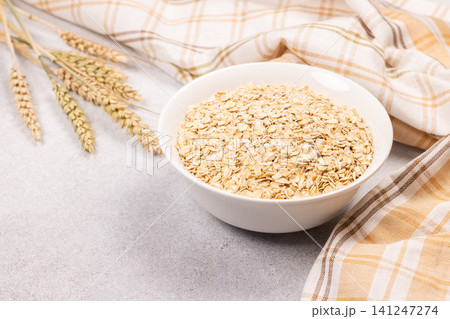 Bowl of raw oats on counter with wheat 141247274