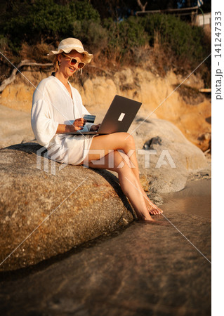 Woman shopping online with credit card on beach Woman shopping online with credit card on beach 141247333