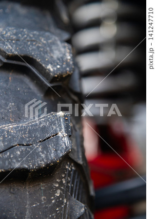 Close-up of rugged tire tread with visible wear and suspension components Close-up of rugged tire tread with visible wear and suspension components 141247710
