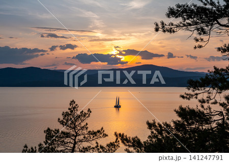 Two yachts on a scenic lake against the backdrop of a picturesque sunrise Two yachts on a scenic lake against the backdrop of a picturesque sunrise 141247791