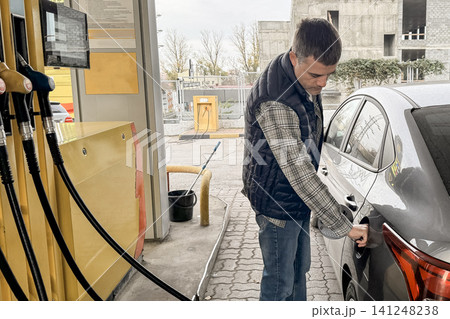 Man refueling car at gas station with yellow pump 141248238
