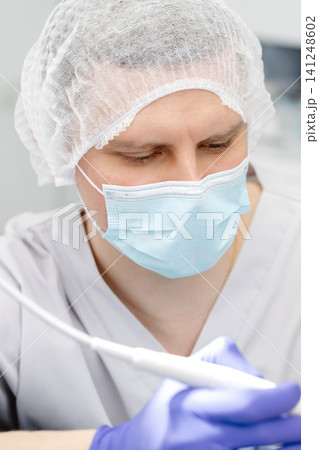 Doctor wearing surgical mask and cap performing medical procedure Doctor wearing surgical mask and cap performing medical procedure 141248602