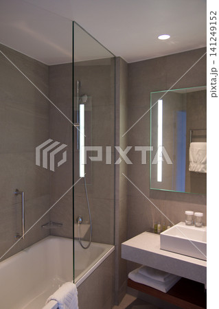 Wroclaw, Poland, June 15, 2018: Bathtub and shower with glass splash guard in luxury hotel bathroom Wroclaw, Poland, June 15, 2018: Bathtub and shower with glass splash guard in luxury hotel bathroom 141249152