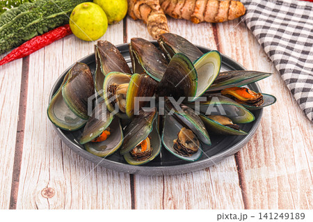 Fresh mussels in black bowl with lime turmeric and chili on wooden table 141249189