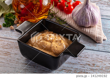 Creamy hummus in black bowl with garlic tomatoes and olive oil on rustic wood Creamy hummus in black bowl with garlic tomatoes and olive oil on rustic wood 141249192