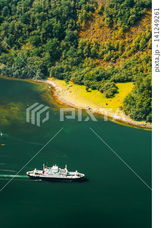 Pleasure boat ship are sailing between fjords. Amazing nature of the Norwegian mountains in Sognefjord. Nature of Norway. Travel concept. Aerial view of a white ferry sailing in a deep green fjord. Pleasure boat ship are sailing between fjords. Amazing nature of the Norwegian mountains in Sognefjord. Nature of Norway. Travel concept. Aerial view of a white ferry sailing in a deep green fjord. 141249261