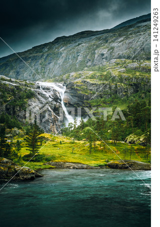 Hiking trail through a pine forest near Kinsarvik. South Fjord, Norway. Giant Waterfall In Valley Of Waterfalls. Husedalen Waterfalls Were A Series Of Four Giant Waterfalls In South Fjord Hiking trail through a pine forest near Kinsarvik. South Fjord, Norway. Giant Waterfall In Valley Of Waterfalls. Husedalen Waterfalls Were A Series Of Four Giant Waterfalls In South Fjord 141249263