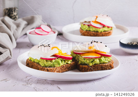 Sandwiches with avocado, radish and poached egg on a plate on the table Sandwiches with avocado, radish and poached egg on a plate on the table 141249326