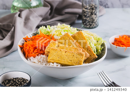 A bowl of rice with fried tofu, Chinese cabbage and carrots on the table A bowl of rice with fried tofu, Chinese cabbage and carrots on the table 141249340