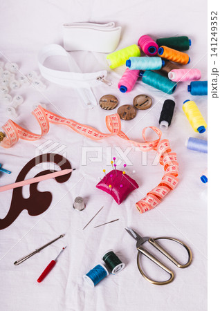 Sewing thread, measuring tape, pattern, and sewing accessories on the white fabric vertical view Sewing thread, measuring tape, pattern, and sewing accessories on the white fabric vertical view 141249352