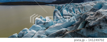 Panoramic view of Glacier Lagoon in southeast Iceland, where the majestic Glacier meets calm waters beneath dramatic clouds and rugged volcanic mountains. Panoramic view of Glacier Lagoon in southeast Iceland, where the majestic Glacier meets calm waters beneath dramatic clouds and rugged volcanic mountains. 141249702