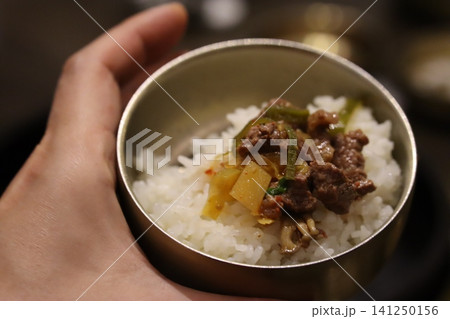 Hand Holding Bowl of Rice with Meat and Vegetables 141250156