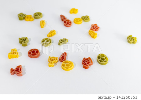 Colorful pasta pieces with football themed shapes scattered on a white surface, creating playful football themed food art. 141250553