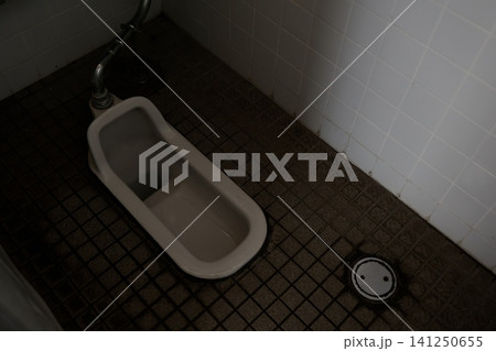 古い和式トイレの便器。タイル床と白いタイル壁の公共トイレ 古い和式トイレの便器。タイル床と白いタイル壁の公共トイレ 141250655