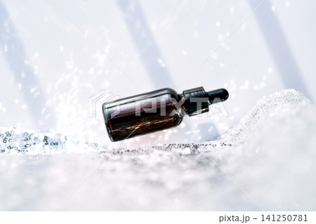 Dropper bottle levitating on a sparkling silver surface Dropper bottle levitating on a sparkling silver surface 141250781