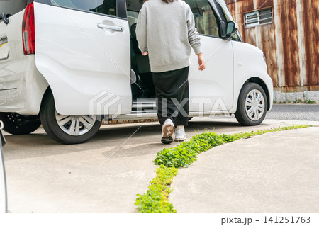 白い軽自動車に向かって歩くグレースウェットの女性の後ろ姿 白い軽自動車に向かって歩くグレースウェットの女性の後ろ姿 141251763