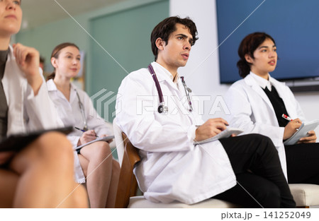 Young female doctor listening and taking notes in lecture hall 141252049