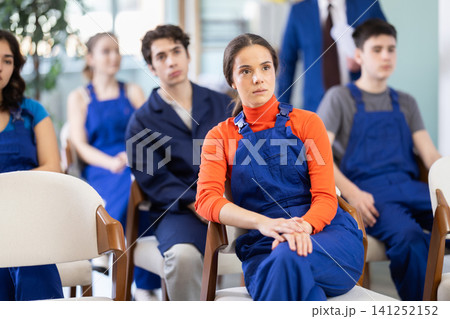 Young female student in blue overalls attending technical seminar Young female student in blue overalls attending technical seminar 141252152