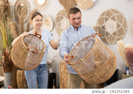 Married couple chooses a wicker laundry basket in furniture store 141252165