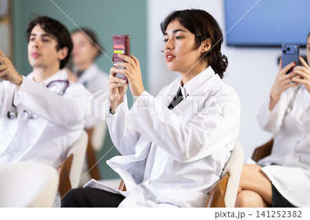 Female doctor scanning QR code with phone in conference hall 141252382